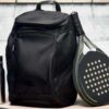 Zaino sportivo Olympic nero in materiale ecologico RPET con racchetta da padel e borraccia in una zona spogliatoio.