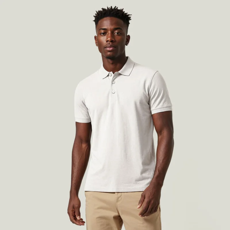 Modello indossa una polo classica bianca in cotone biologico con spacchetti laterali, abbinata a pantaloni beige.